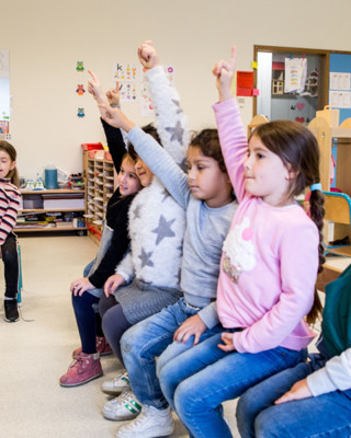 Gretige Kleuters Op Een Bank In De Klas Met Handjes In De Lucht Rh