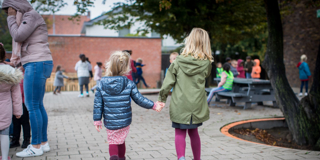 Twee Meisjes Op Speelplaats Hand In Hand En Op De Rug Gezien