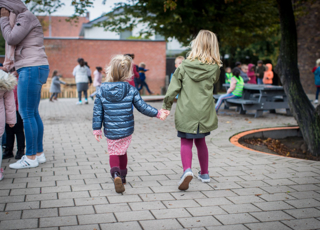 Twee Meisjes Op Speelplaats Hand In Hand En Op De Rug Gezien