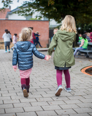 Twee Meisjes Op Speelplaats Hand In Hand En Op De Rug Gezien